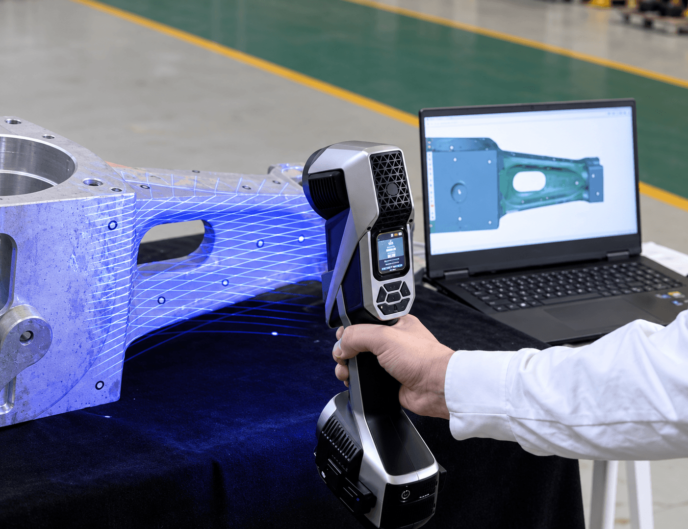 Industrial 3D scanning of a machined component with corresponding digital geometry displayed on a laptop.