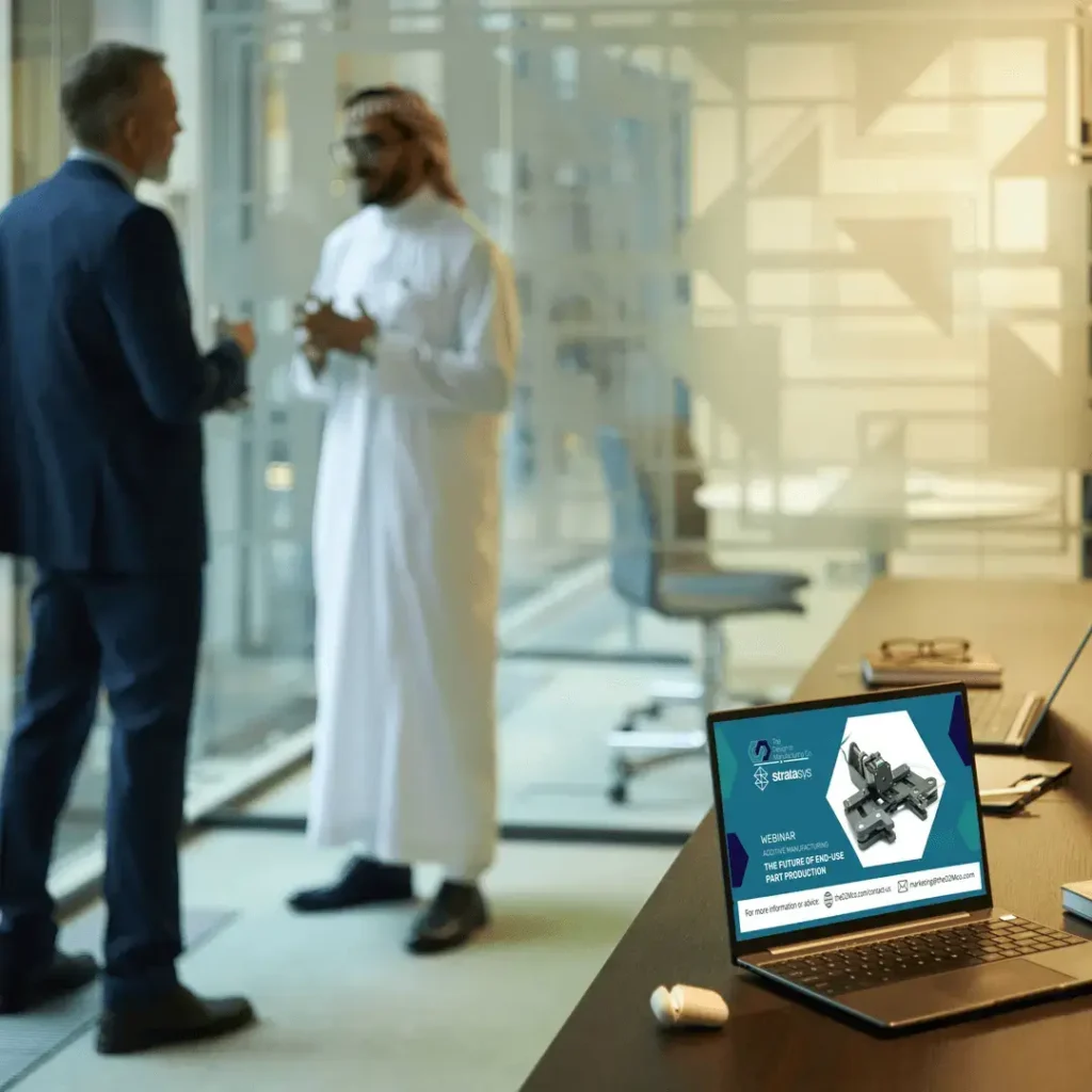Two professionals in discussion with laptop showing the D2M co additive manufacturing webinar